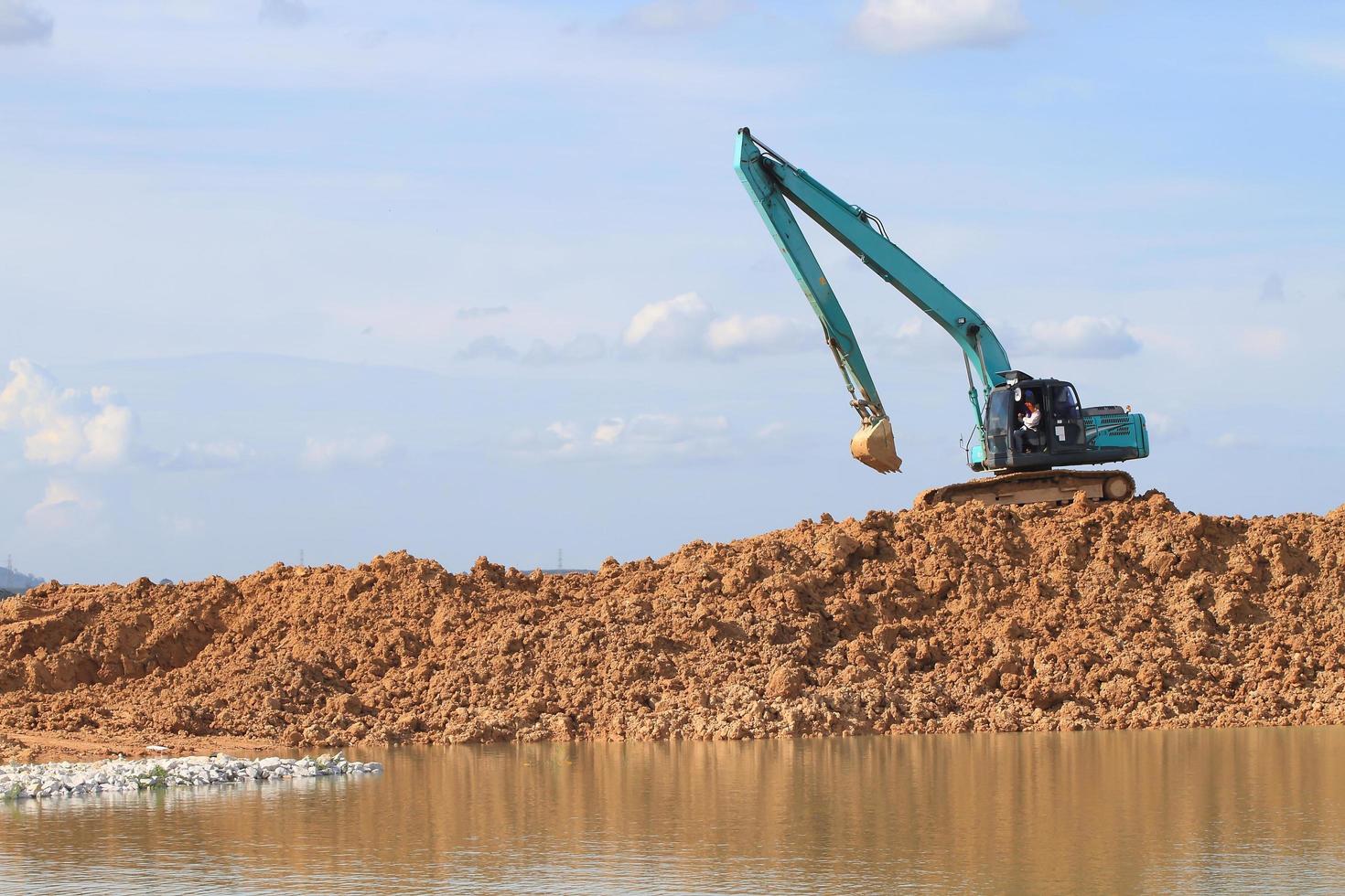 escavatore situato vicino a un fiume e pronto per il lavoro foto