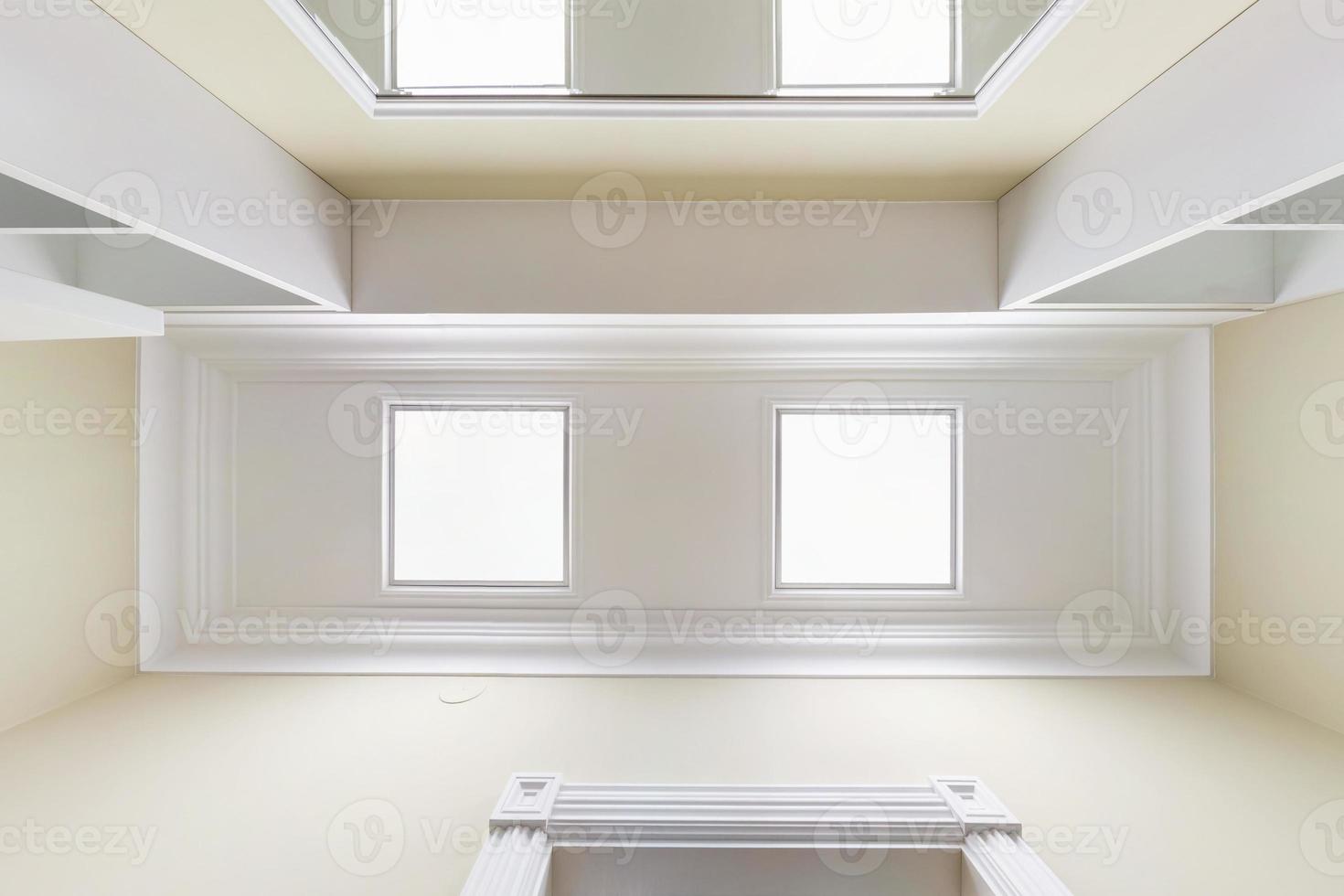 guardando in alto sul soffitto sospeso con lampade alogene e costruzione di cartongesso in una stanza vuota in appartamento o casa. soffitto teso bianco e di forma complessa. foto