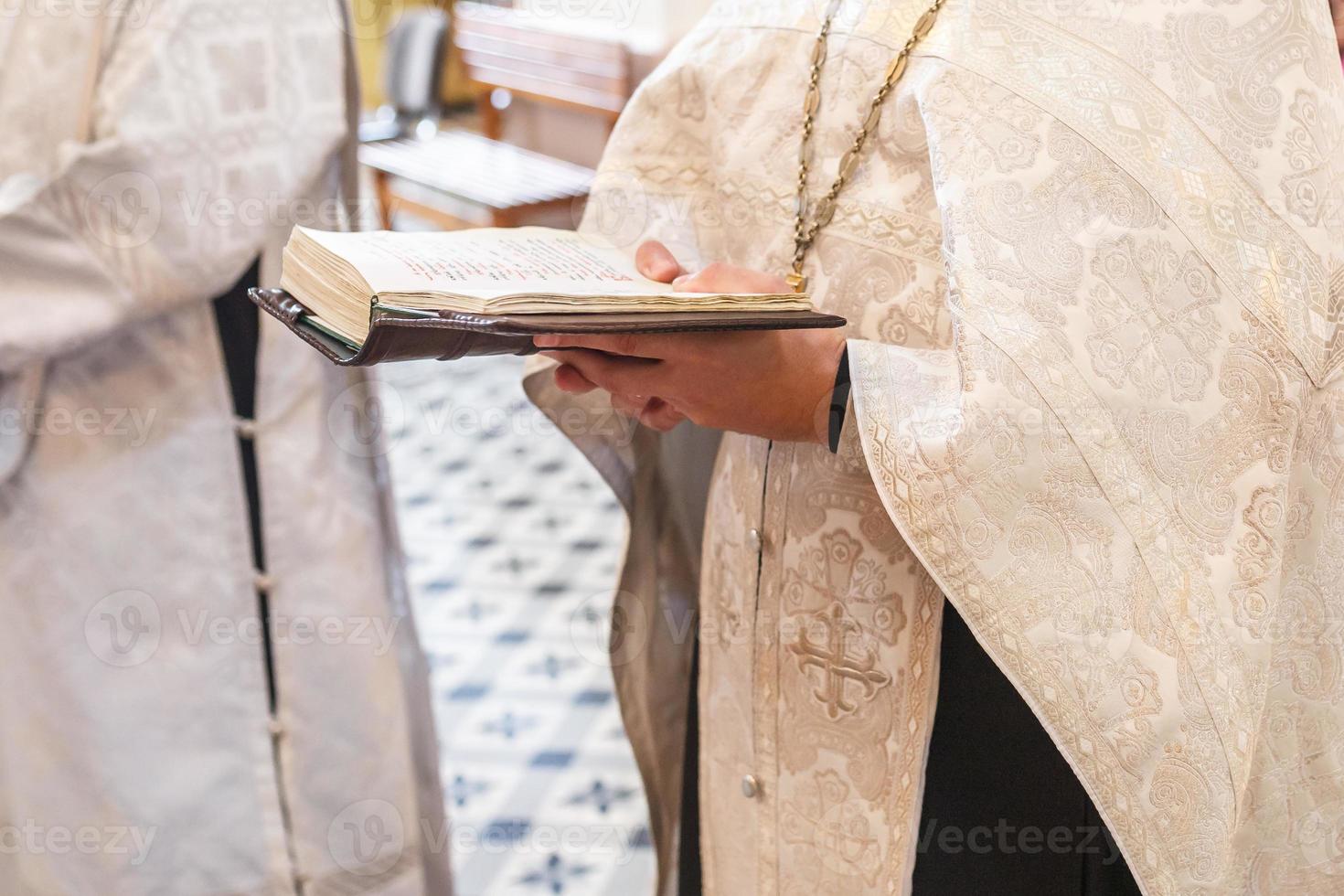 sacerdote in una chiesa ortodossa legge una preghiera dalla Bibbia durante un servizio di culto foto