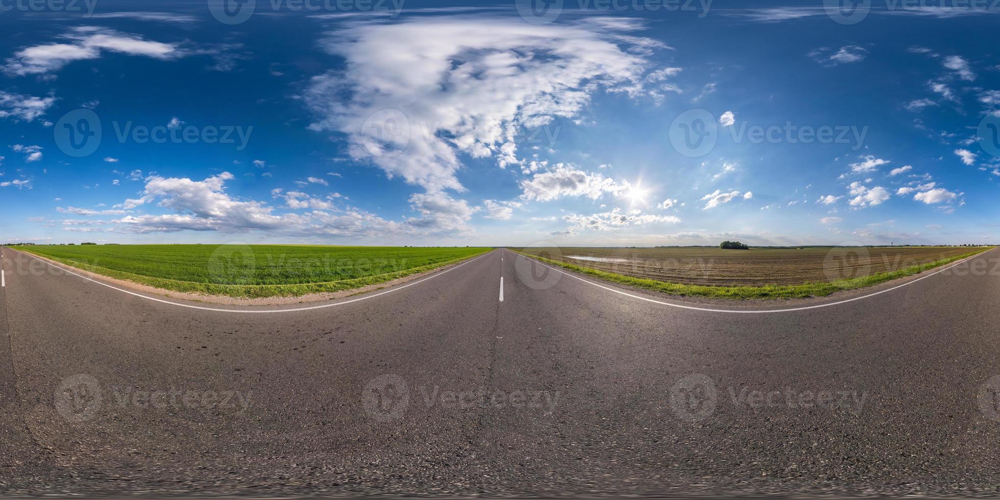 panorama hdri completo sferico senza soluzione di continuità angolo di 360 gradi su strada asfaltata senza traffico tra campi con cielo azzurro in proiezione equirettangolare, contenuto vr ar foto