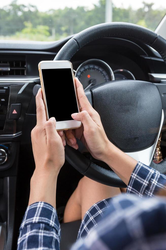 giovane conducente femminile che utilizza lo smartphone touch screen in un'auto. foto