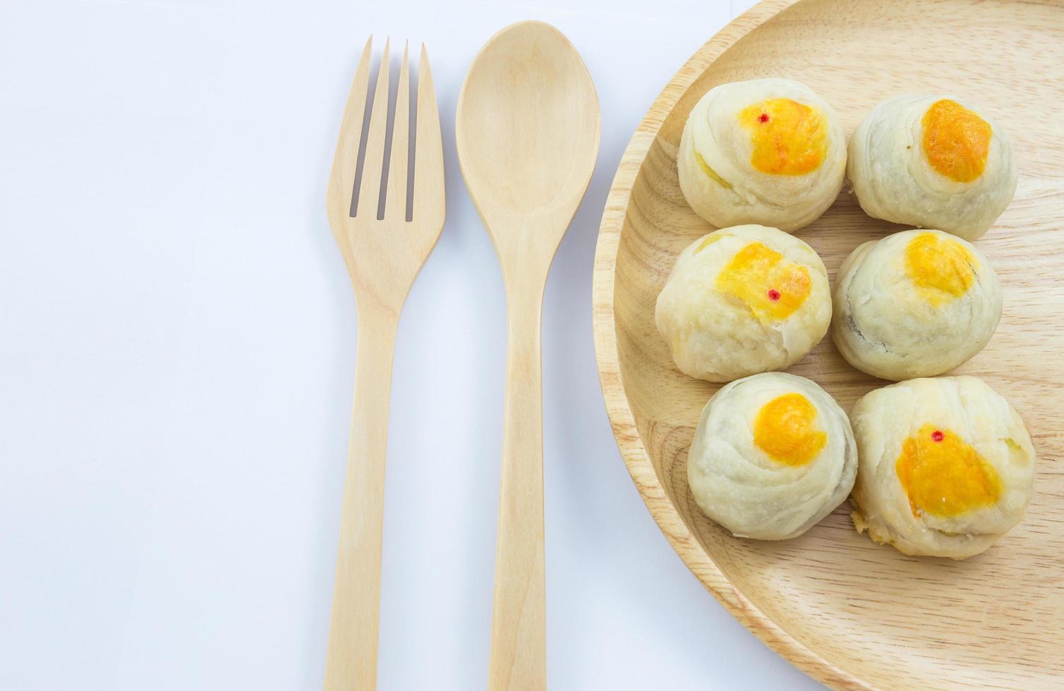 fagiolo cinese della pasticceria o mooncake con il tuorlo d'uovo sul piatto di legno e sulla forchetta del cucchiaio foto