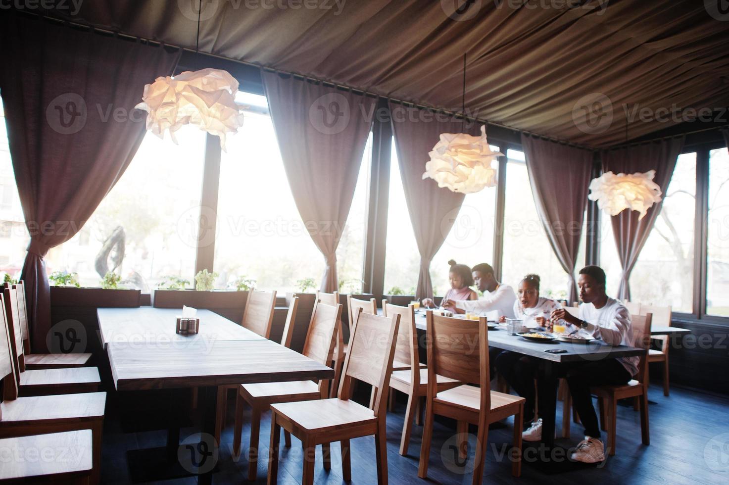 felici amici africani seduti, chiacchierando al bar e mangiando cibo. gruppo di persone di colore che si incontrano al ristorante e cenano. foto