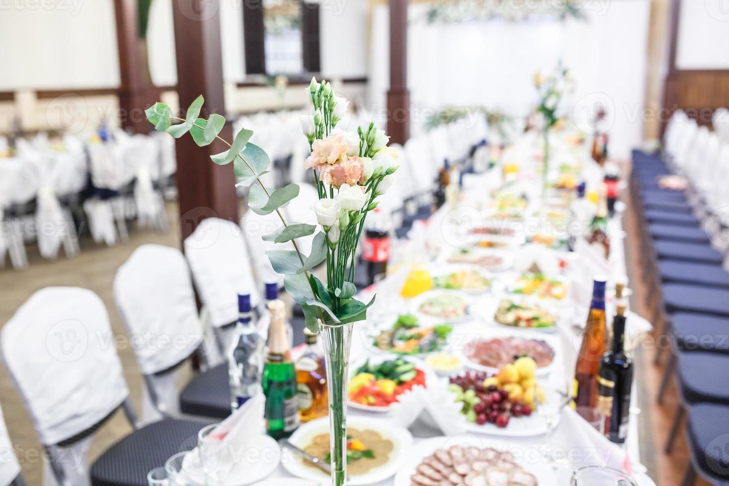 bellissimi fiori su un'elegante tavola da pranzo nel giorno del matrimonio. decorazioni servite sulla tavola festiva su sfondo sfocato foto