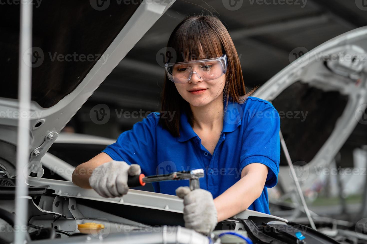 concetto di riparazione automatica. un tuttofare asiatico che indossa una camicia blu in un garage. felice meccanico femminile nel centro servizi di riparazione auto. ispettore meccanico di un'auto o di un veicolo foto