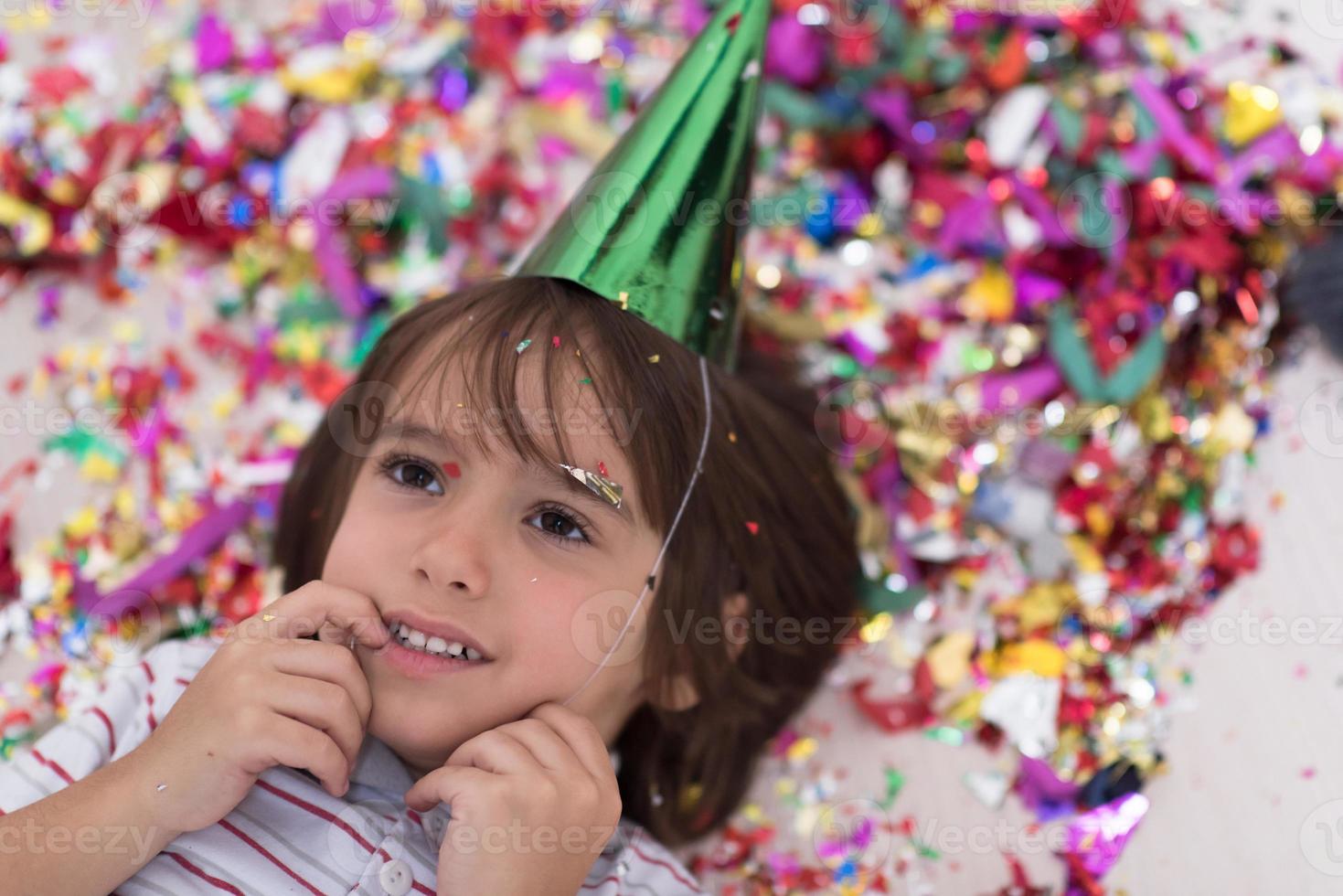 bambino che soffia coriandoli sdraiato sul pavimento foto