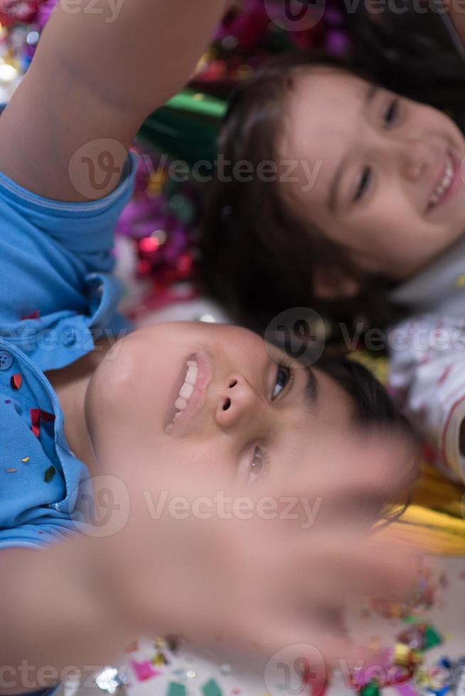 bambini che soffiano coriandoli sdraiati sul pavimento foto