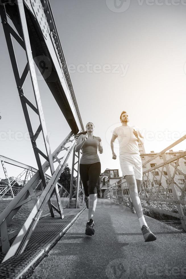 giovane coppia che fa jogging attraverso il ponte della città foto