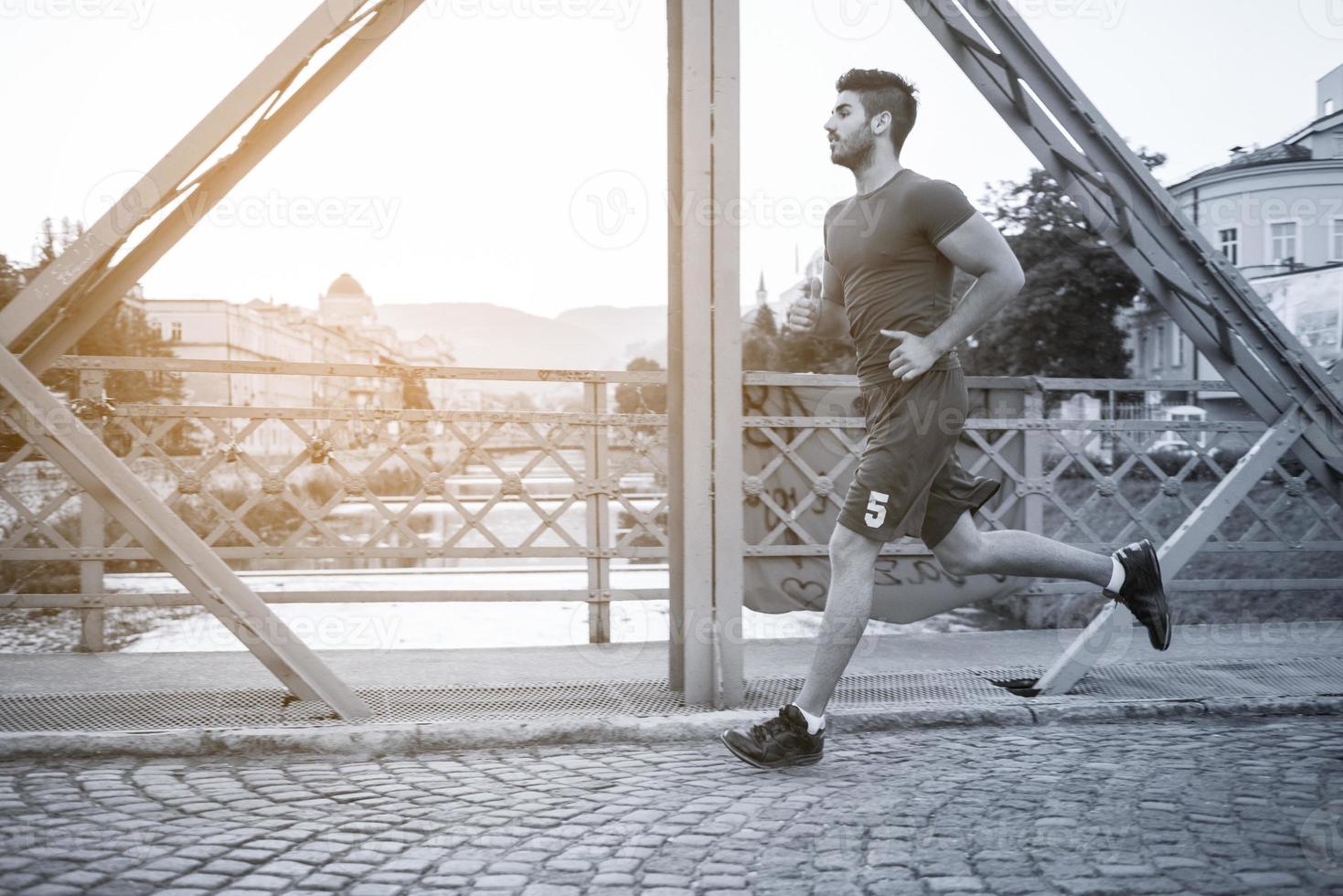 uomo che fa jogging attraverso il ponte al mattino soleggiato foto