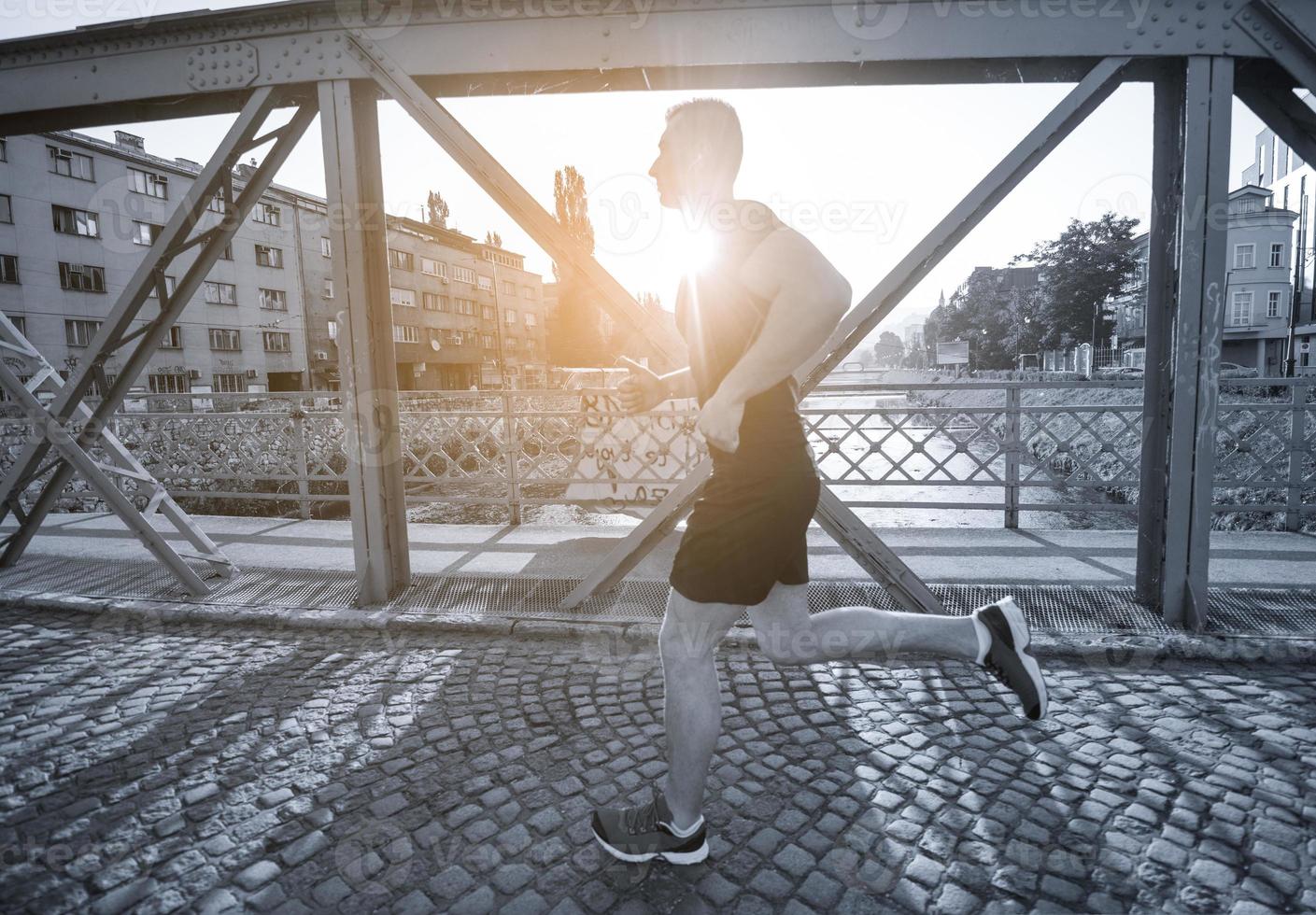 uomo che fa jogging attraverso il ponte al mattino soleggiato foto