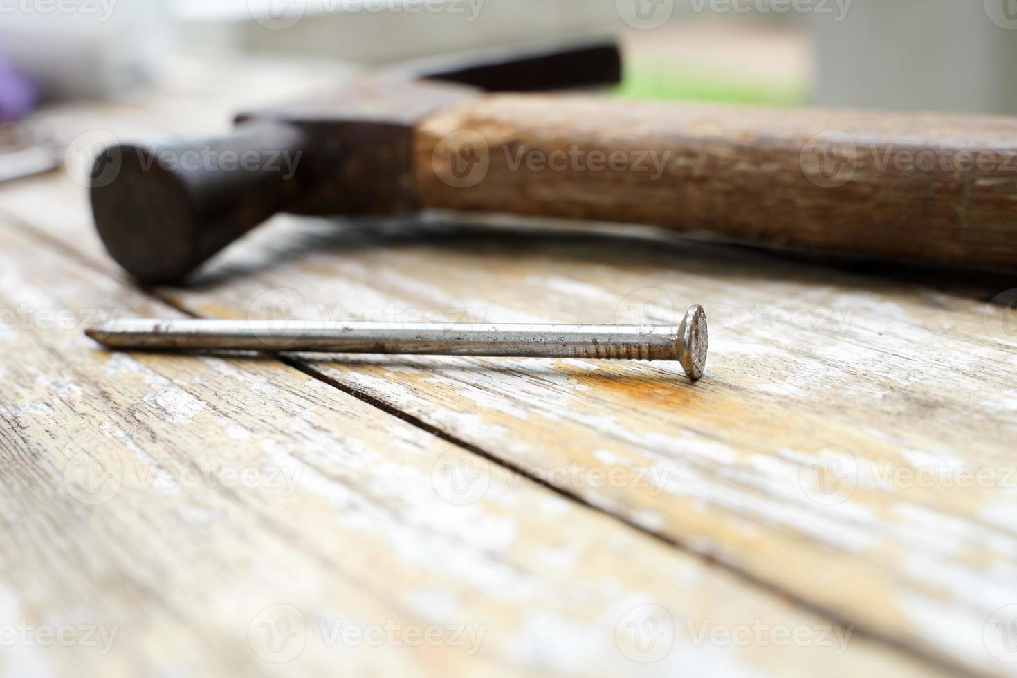 martello e chiodi su fondo di legno, testa di legno e ruggine martello di ferro sdraiato su tavola di legno con officina all'aperto. foto