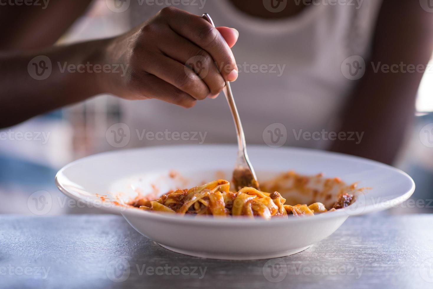 una giovane donna afroamericana che mangia pasta foto