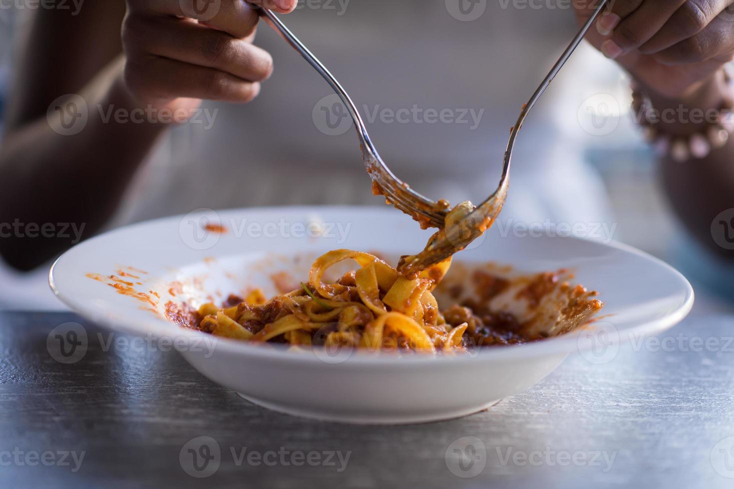 una giovane donna afroamericana che mangia pasta foto