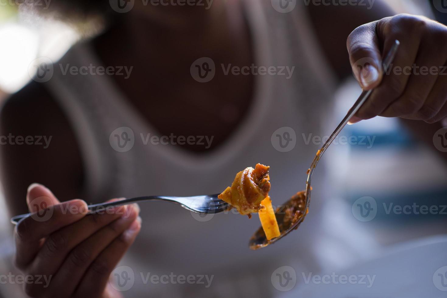 una giovane donna afroamericana che mangia pasta foto