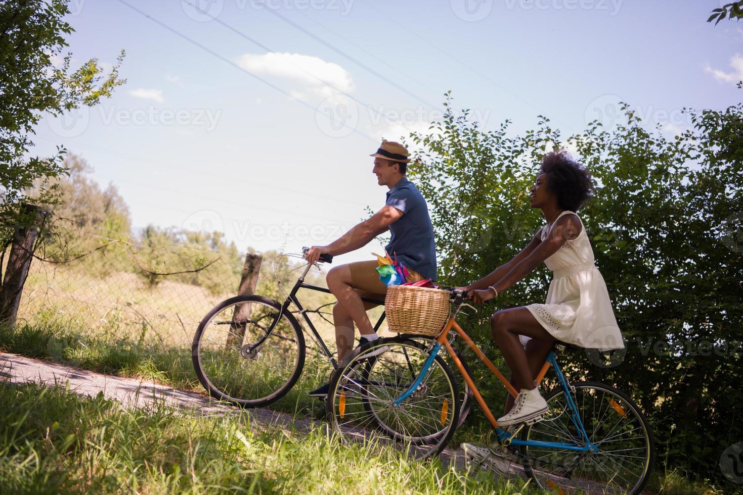 giovane coppia multietnica che fa un giro in bicicletta nella natura foto