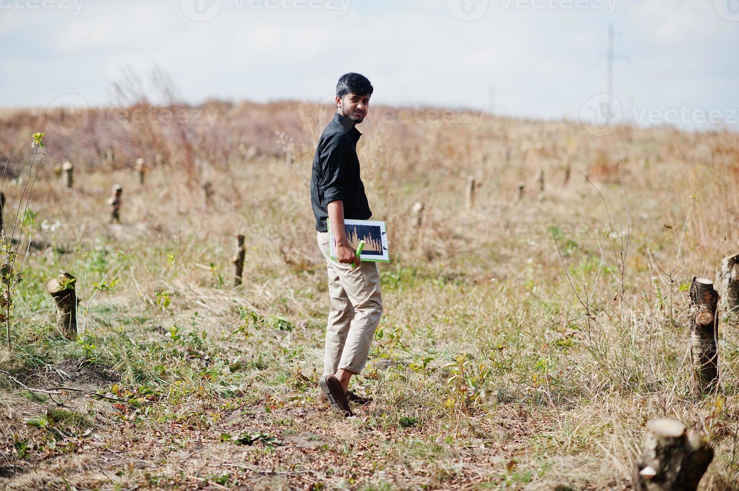 agronomo agricoltore del sud asiatico con appunti che ispeziona alberi tagliati nel giardino della fattoria. concetto di produzione agricola. foto