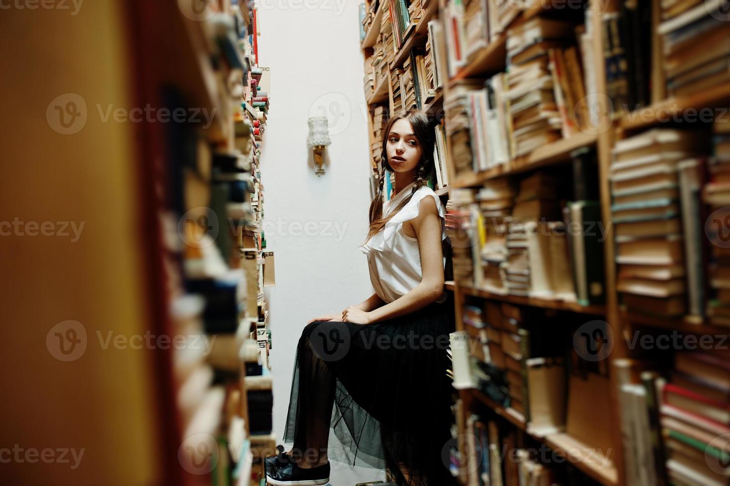 ragazza con le trecce in camicetta bianca alla vecchia biblioteca. foto