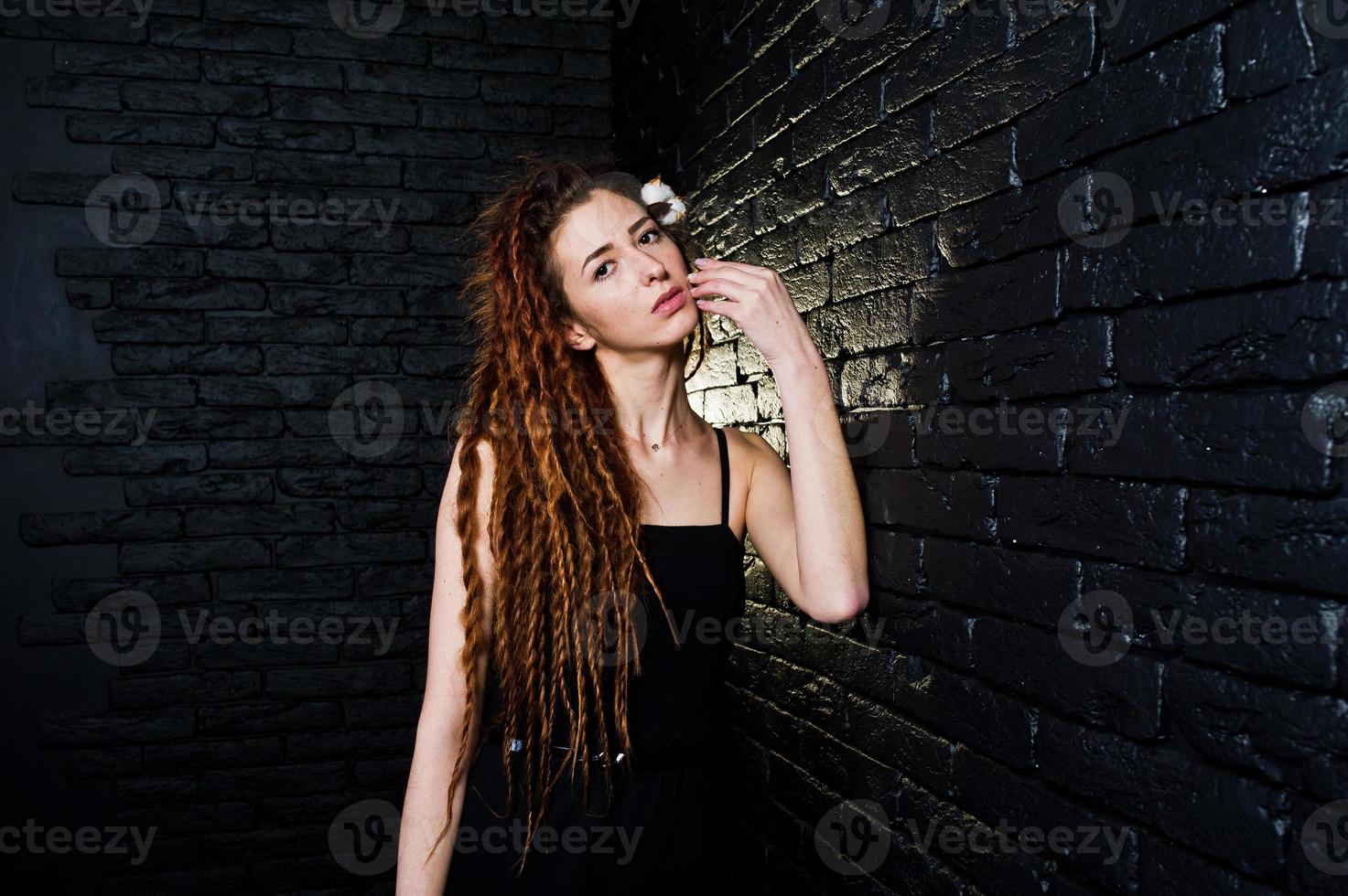 tiro in studio di una ragazza in nero con dreadlocks su sfondo di mattoni. foto