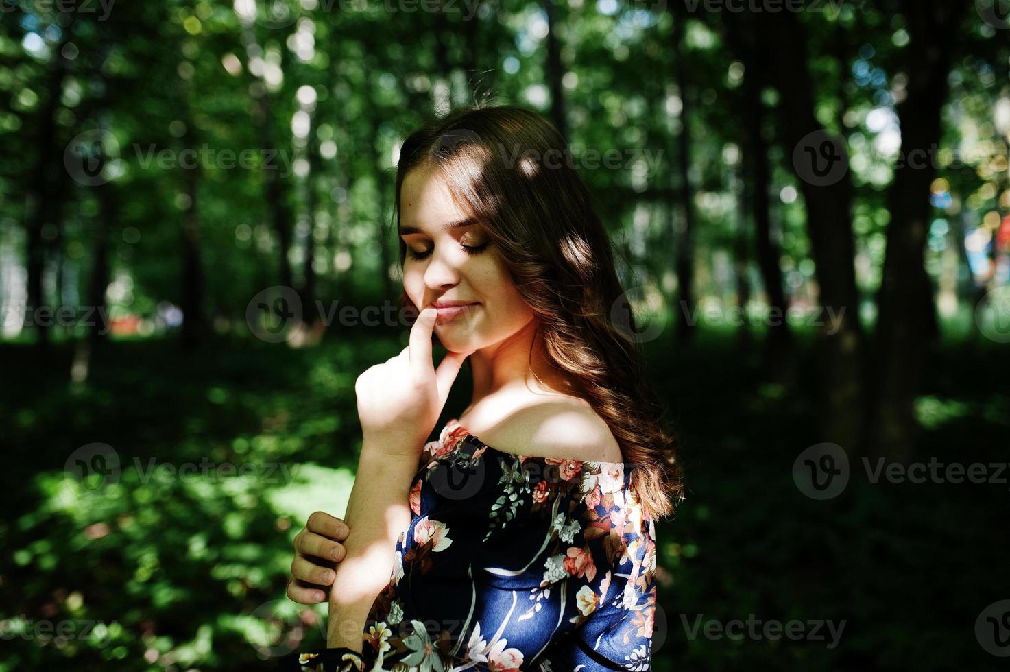 ritratto di una favolosa ragazza in un bel vestito con un'elegante acconciatura riccia in posa nella foresta o nel parco. foto