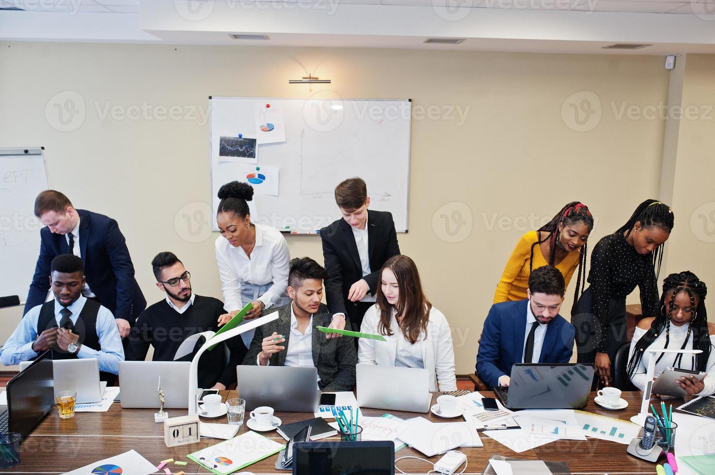 giovani creativi multirazziali in un ufficio moderno. gruppo di giovani uomini d'affari stanno lavorando insieme con laptop, tablet. team di freelance di successo nel coworking. foto