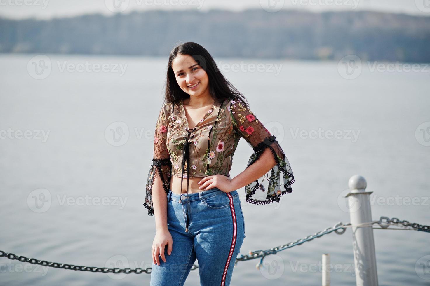 bella ragazza modello latino dell'Ecuador indossa jeans in posa contro il lago. foto