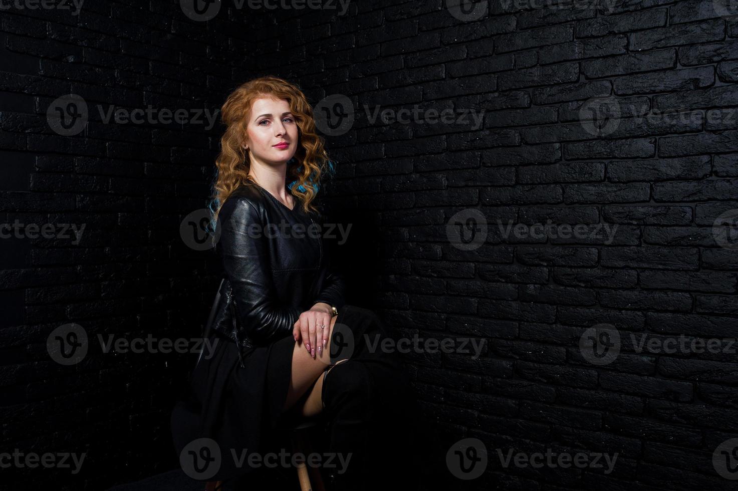 ragazza capelli ricci in giacca di pelle in studio contro il muro di mattoni neri. foto