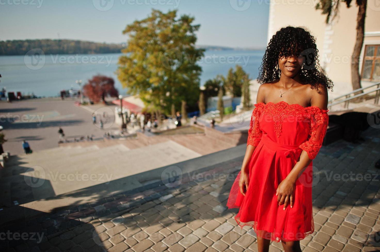 donna riccia afro francese alla moda alla moda in posa al giorno d'autunno in abito rosso. modello femminile africano nero. foto