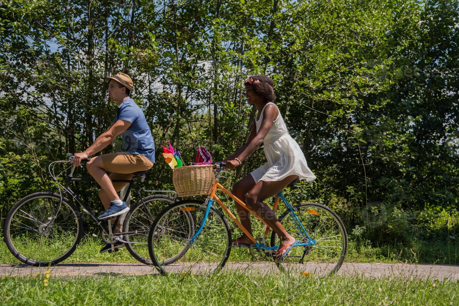 giovane coppia multietnica che fa un giro in bicicletta nella natura foto