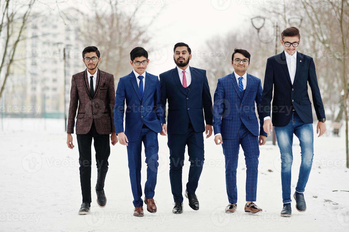 un gruppo di cinque uomini d'affari indiani in giacca e cravatta in posa e passeggiate all'aperto nella giornata invernale in Europa. foto