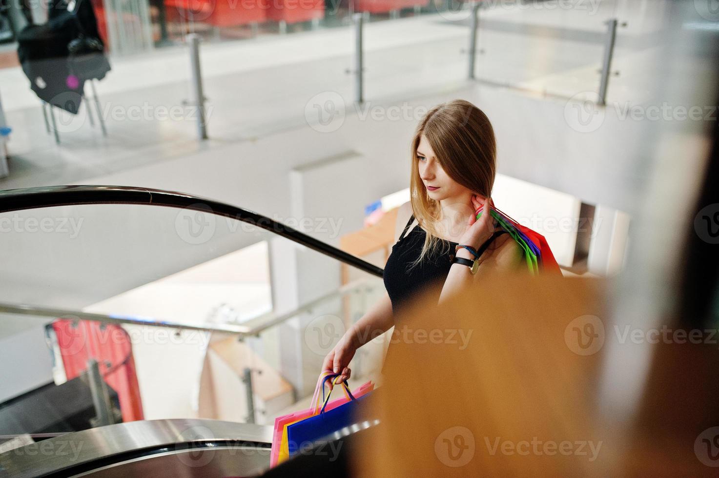 ragazza con le borse della spesa nel centro commerciale sulla scala mobile. foto