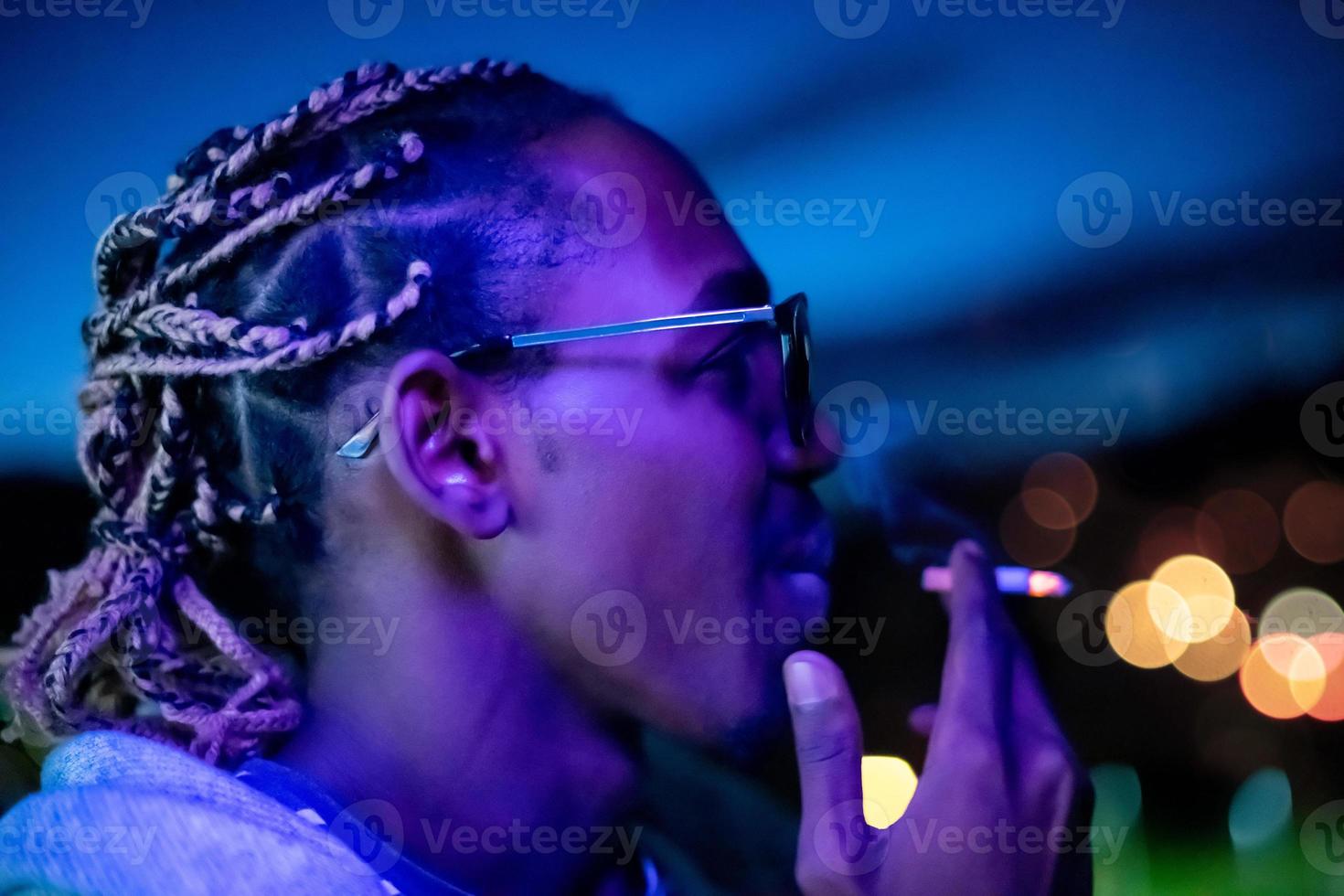 uomo afroamericano che fuma sigaretta di notte foto