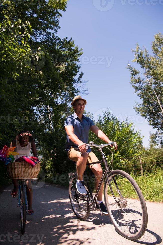 giovane coppia multietnica che fa un giro in bicicletta nella natura foto