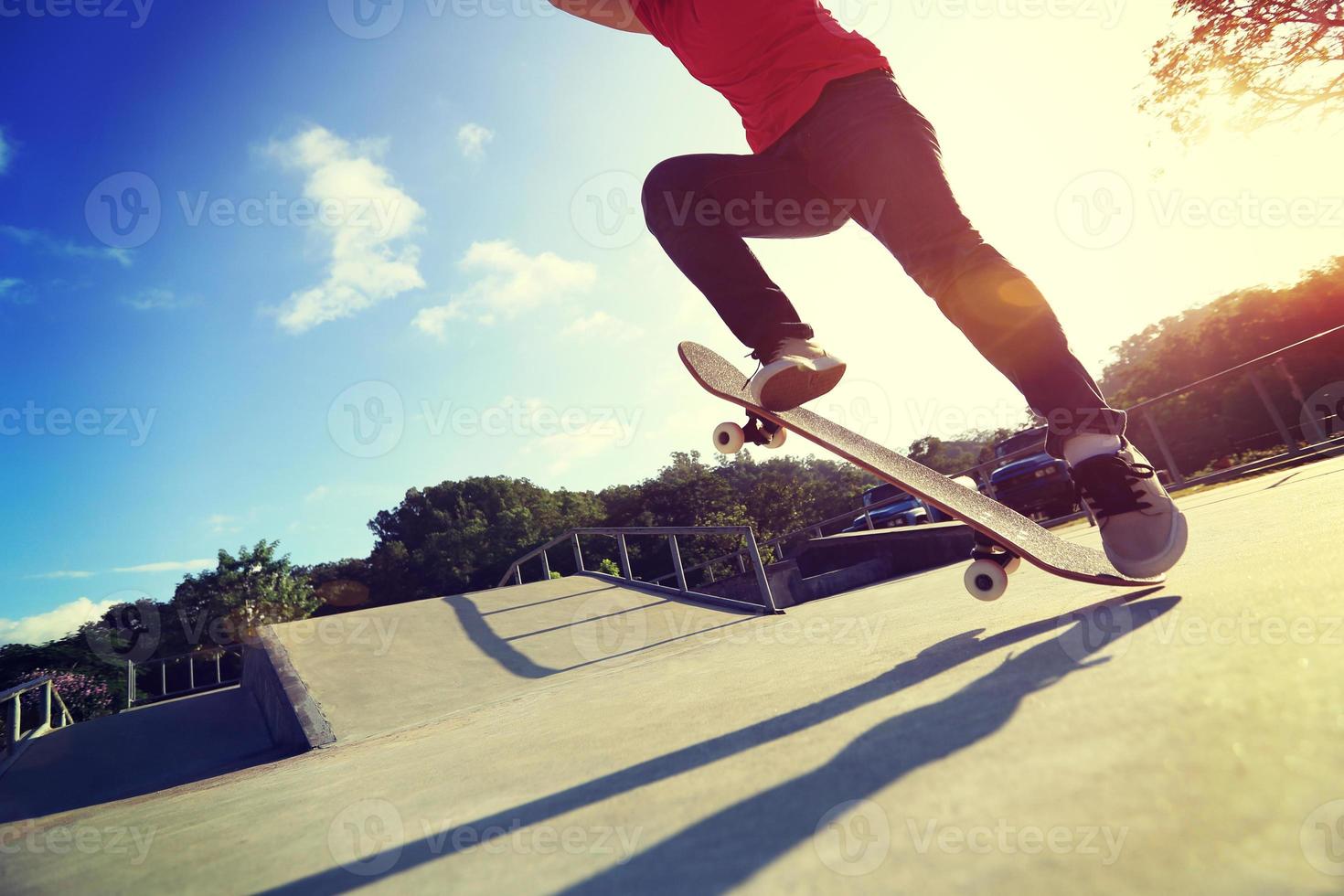 gambe di skateboarder facendo un trucco ollie allo skatepark foto