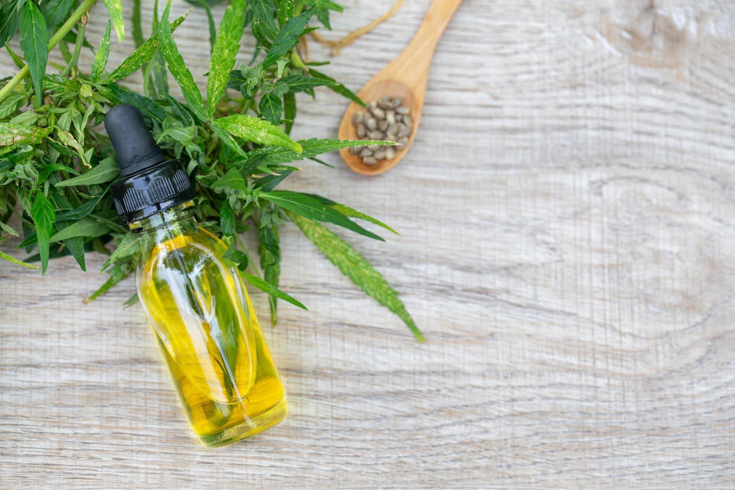 Estratto di cannabis con olio di cbd, bottiglie di olio di canapa e fiori di canapa su un tavolo di legno, concetto di cannabis medica, spazio per la copia. foto