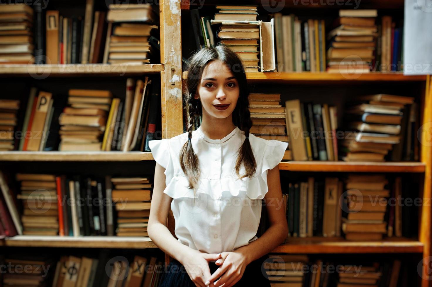 ragazza con le trecce in camicetta bianca alla vecchia biblioteca. foto