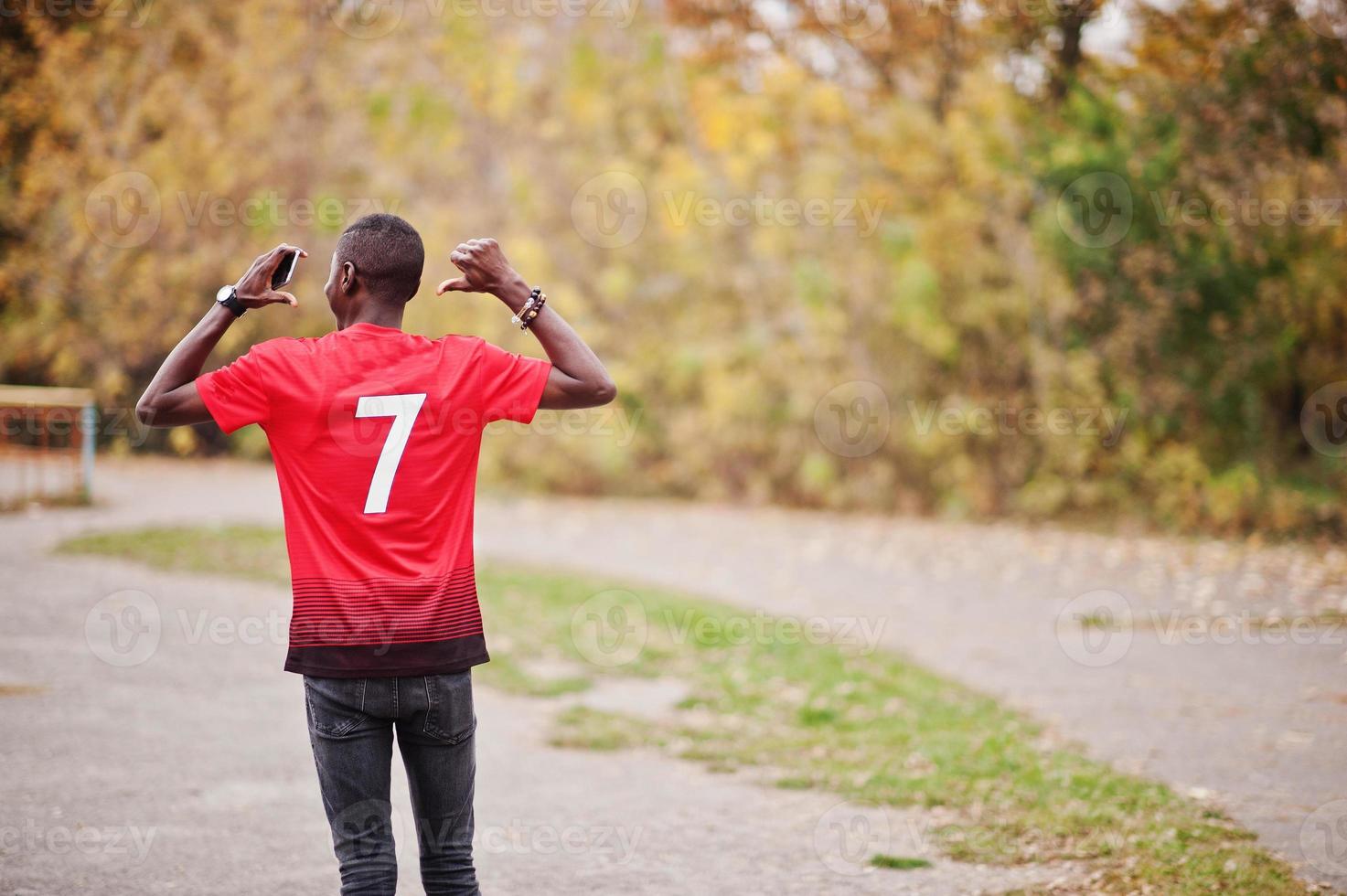 uomo afroamericano in maglietta rossa sportiva da calcio con numero 7 contro il parco autunnale. foto