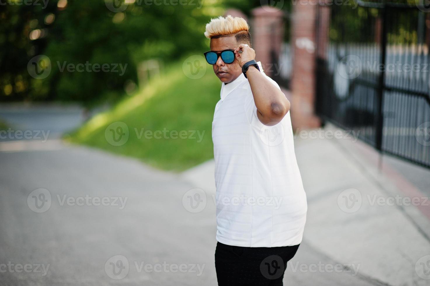 elegante ragazzo musulmano arabo con originariamente capelli e occhiali da sole in posa per le strade. foto