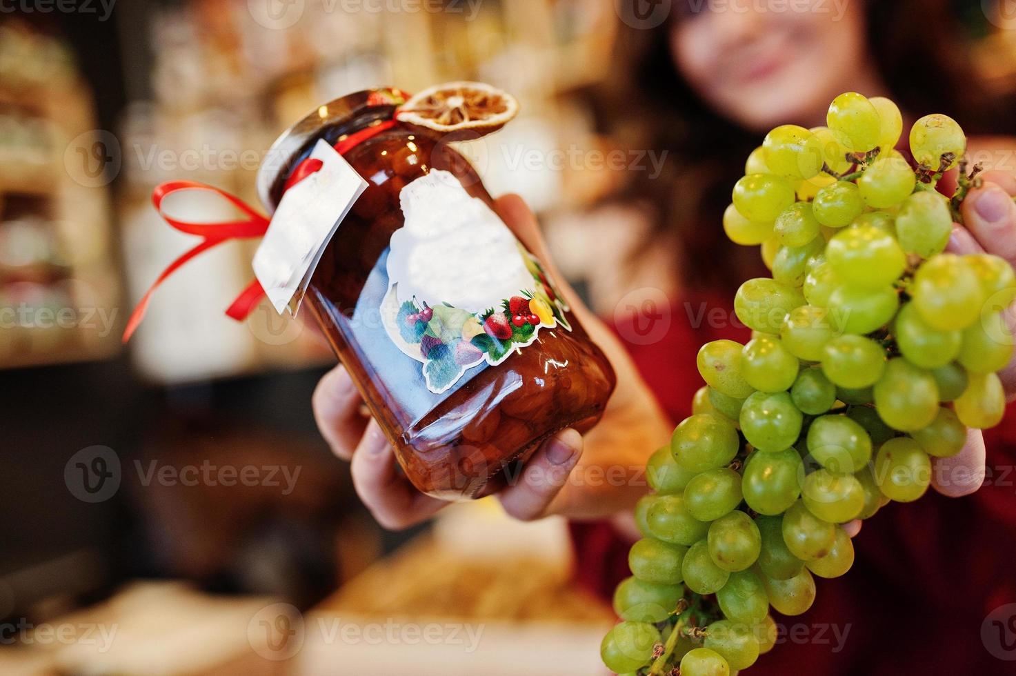 ragazza in rosso con marmellata d'uva in un barattolo sul negozio di frutta. foto