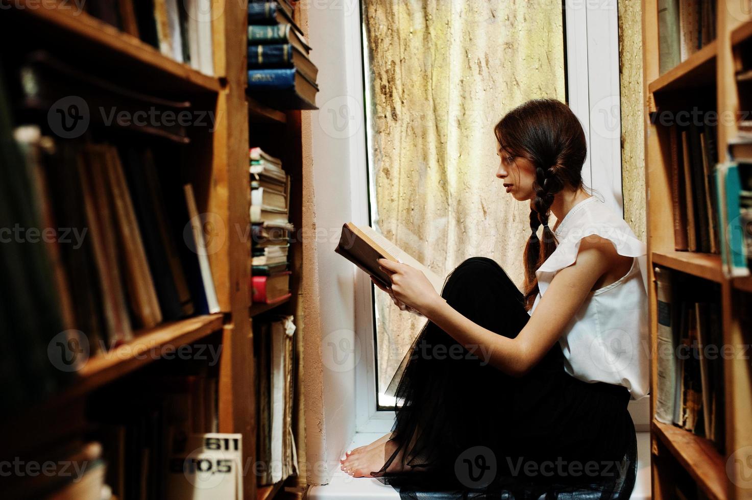 ragazza con le trecce in camicetta bianca alla vecchia biblioteca. foto