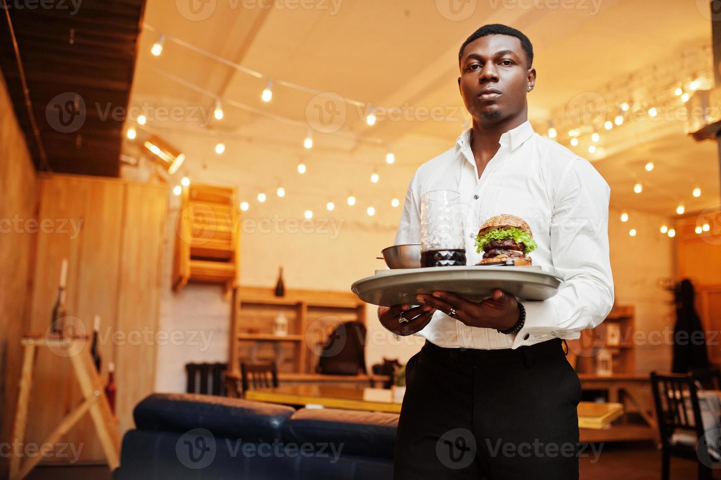 giovane cameriere afroamericano uomo tenere vassoio con hamburger al ristorante. foto