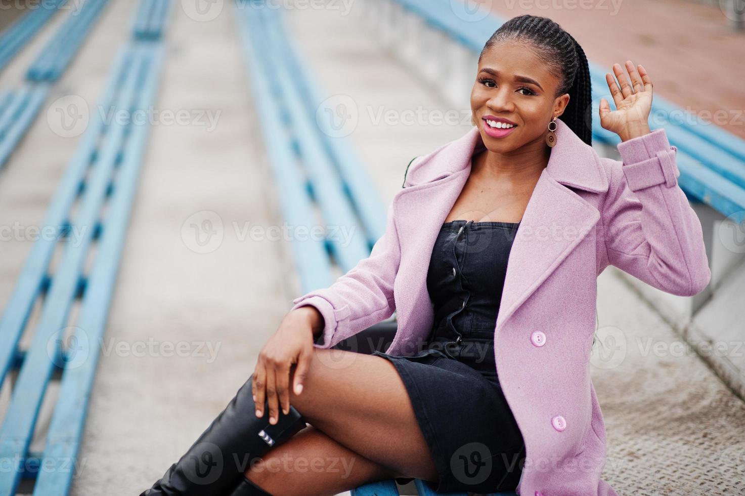 giovane ed elegante bella donna afroamericana in strada alle gradinate dello stadio, indossando il cappotto dell'abito di moda. foto