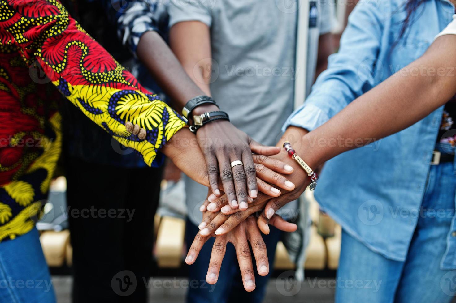 gruppo di cinque studenti universitari africani che trascorrono del tempo insieme nel campus nel cortile dell'università. amici afro neri che studiano. tema dell'educazione. mani sulle mani. foto