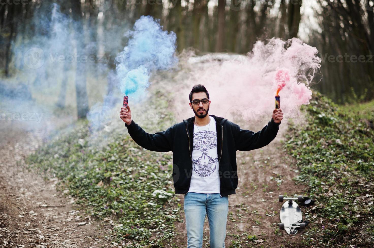 l'uomo arabo di street style con gli occhiali tiene il bagliore della mano con una bomba fumogena rossa e blu. foto