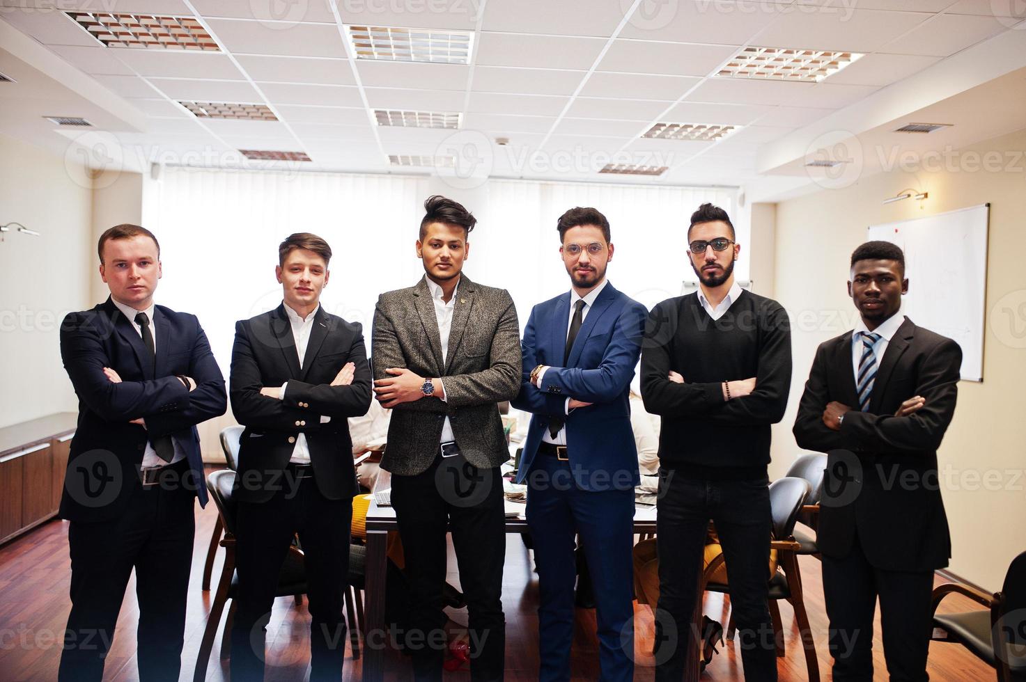 sei uomini d'affari multirazziali in piedi in ufficio con le braccia incrociate. gruppo eterogeneo di dipendenti maschi in abiti formali. foto