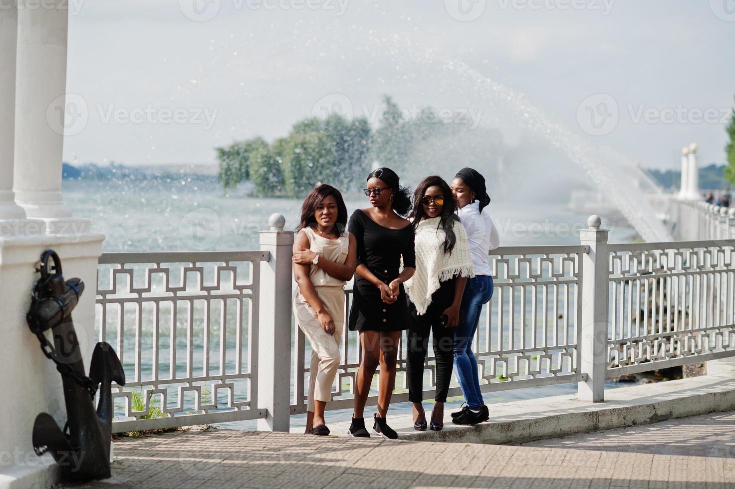 gruppo di quattro ragazze afroamericane che si divertono contro il lago con fontane. foto