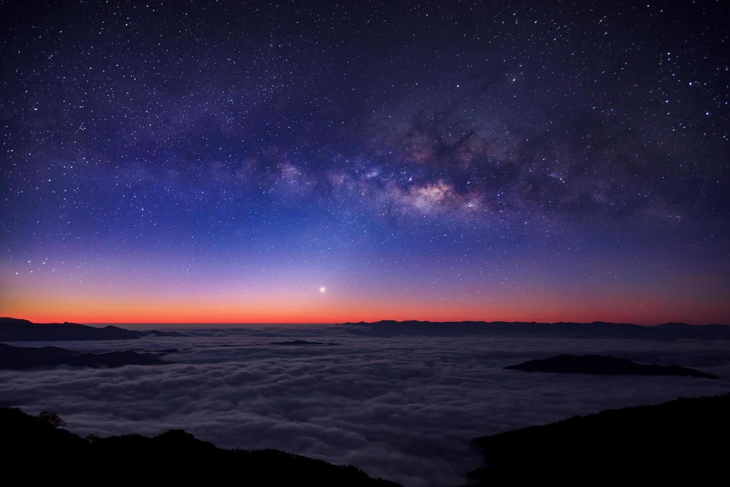 via lattea sul cielo notturno sopra la montagna nebbiosa foto