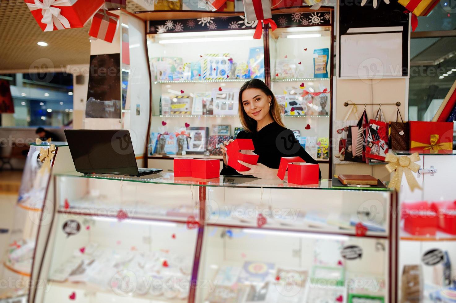 ritratto di giovane donna caucasica venditore tenere scatole regalo rosse. piccola impresa di negozio di souvenir di caramelle. foto