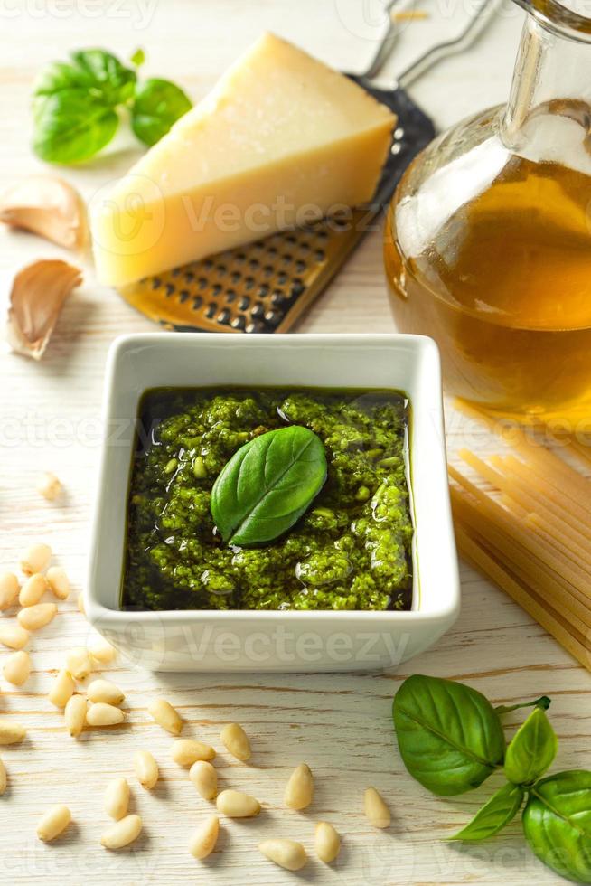 salsa di pesto fatta in casa con ingredienti alimentari su fondo di legno bianco foto