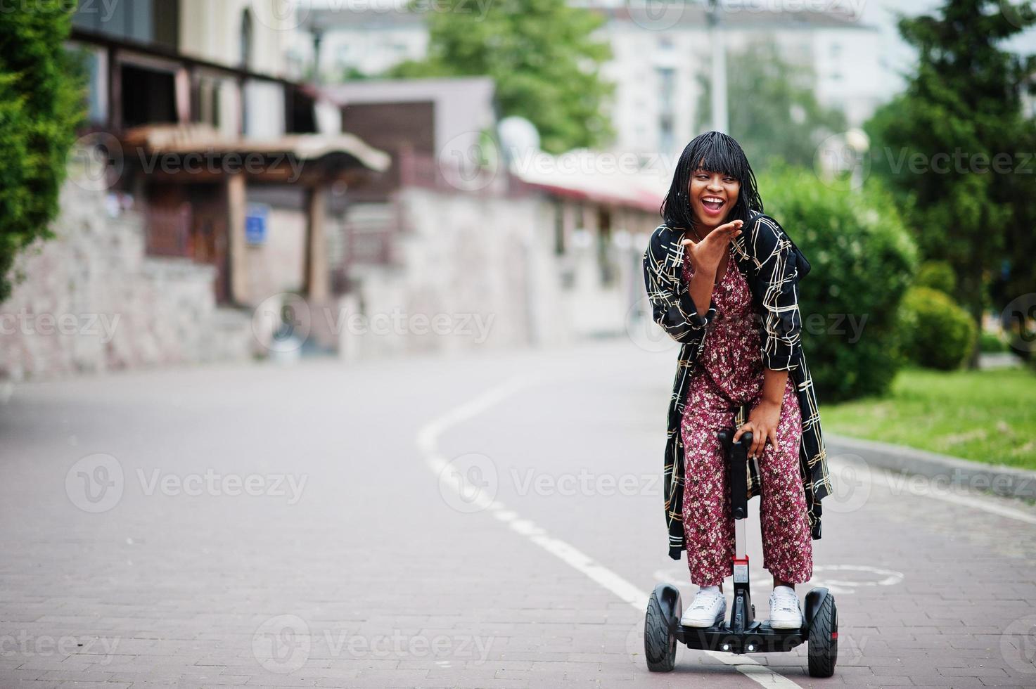 bella donna afroamericana utilizzando segway o hoverboard. ragazza nera su scooter elettrico autobilanciante a doppia ruota. foto