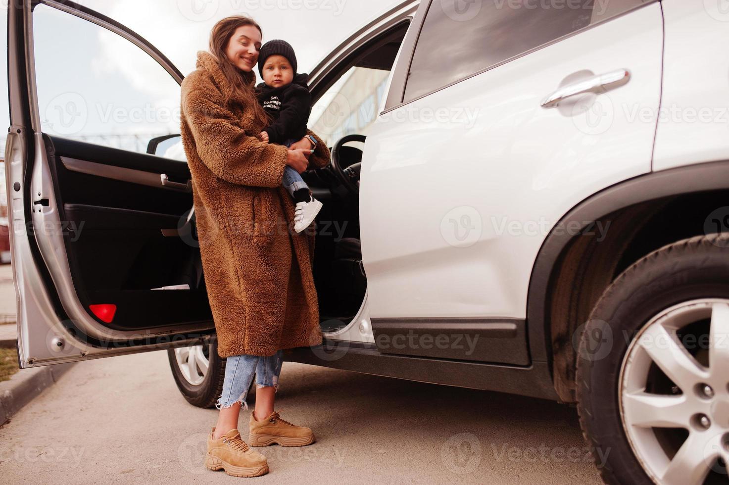 la giovane madre e il bambino stanno vicino alla loro auto suv. concetto di guida di sicurezza. foto